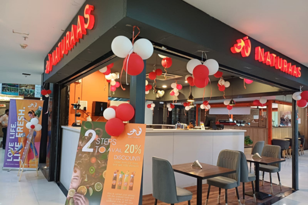 A brightly lit, mall retail space for "Naturaas," featuring a counter and promotional signage for "Super Combos.