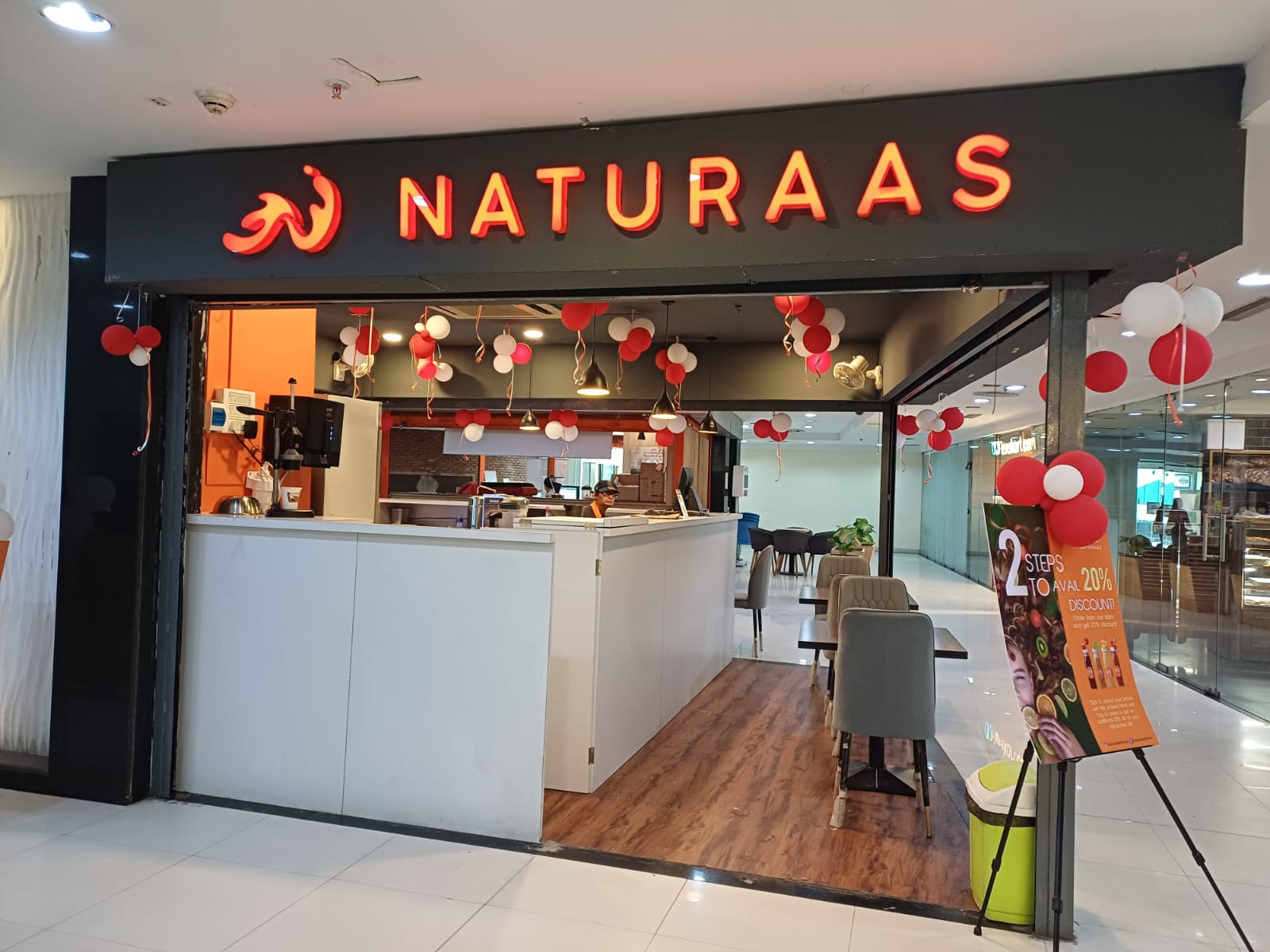 This image showcases a vibrant, ready-to-occupy retail store space for rent ideally suited for a Quick Service Restaurant (QSR) or cafe. Featuring a modern glass frontage, wooden flooring, and inviting seating, this retail space demonstrates the high-quality infrastructure available for F&B brands. Located in the bustling commercial hub of Salt Lake Sector 5, such spaces offer excellent visibility and high footfall from the surrounding corporate workforce, ensuring your business gets the attention it deserves from day one.