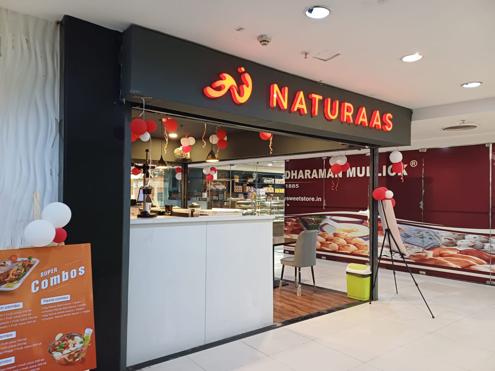 A brightly lit, mall retail space for "Naturaas," featuring a counter and promotional signage for "Super Combos.